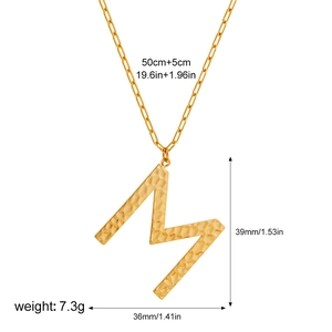Detail of gold letter M pendant with hammered texture on a paperclip link chain