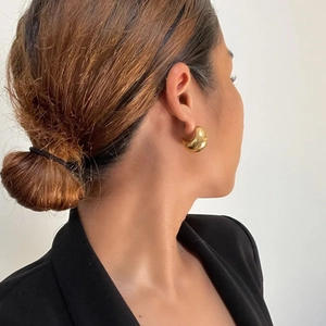 Close-up of chunky gold hoop earrings with a polished mirror finish on model