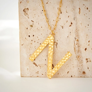Detail of gold capital letter Z pendant with hammered texture on a paperclip chain