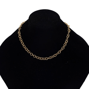 Detailed close-up of golden circular link chain necklace on a black velvet display bust
