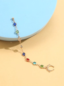 Détail de la chaîne nez-oreille dorée avec gemmes colorées et clip à motifs ciselés