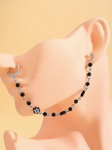 Détail de la chaîne nez-oreille punk avec perles noires et petite fleur décorative
