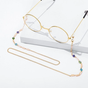 Detail of gold metal glasses chain with colorful devil eye charms and pink beads