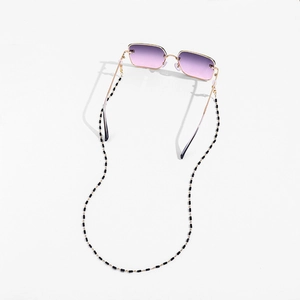 Detail of Y2K sunglasses with purple gradient lenses and black-and-white beaded chain