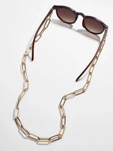 Detail of gold paperclip eyewear chain with anti-slip rings on tortoise sunglasses