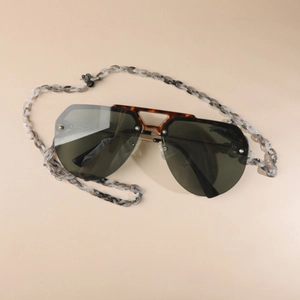 Detailed view of oversized tortoiseshell sunglasses with acrylic chain in black and white