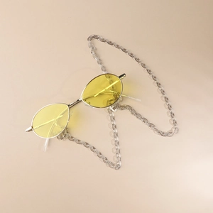 Close-up of yellow lens sunglasses with silver metal frame and transparent acrylic chain