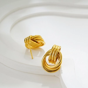 Detailed view of layered 18K gold hoop earrings with polished mirror finish on white stand