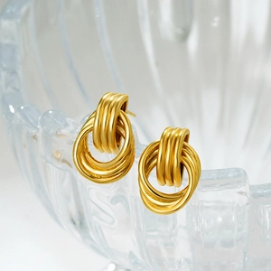 Detailed view of 18K gold and silver intertwined hoop earrings on vintage glassware