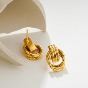 Detailed close-up of 18K gold and silver triple-layered coil earrings on stone display