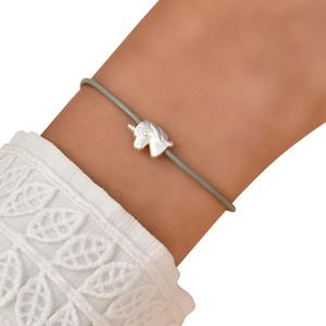 Close-up of a delicate unicorn charm bracelet with minimalist grey cord on a wrist