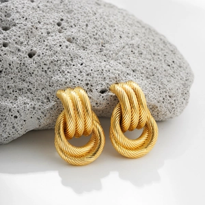 Macro detail of 18K gold intertwined twisted hoop earrings with textured rope design
