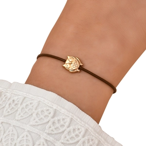 Detail of a minimalist brown cord bracelet with a finely crafted golden owl charm