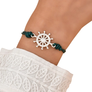 Close-up of nautical steering wheel charm on a dark green leather bracelet for women