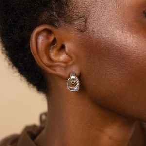 Close-up of triple-layered silver coil hoop earrings worn by a model in warm light