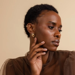 Detailed view of 18K gold and silver mixed layered hoop earrings on model ear