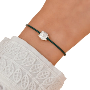 Detail of dark green woven bracelet featuring an owl charm on a white lace background