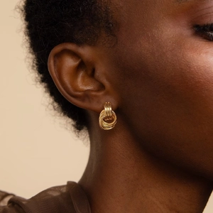 Close-up of 18K gold-layered triple coil earrings worn by a model in warm light