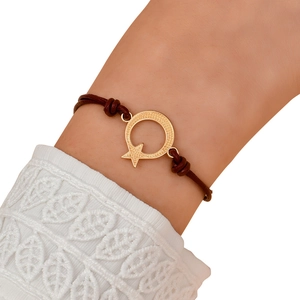 Detail of star and moon gold pendant on dark brown leather cord bracelet for women