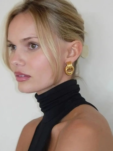 Detail shot of multi-layer twisted golden hoop earrings worn by a model in a high-end style