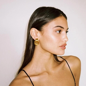 Close-up of model wearing minimalist 18K gold double hoop earrings with a layered twist