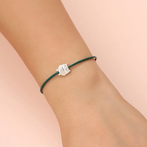 Close-up of minimalist dark green cord bracelet with vintage silver owl charm on wrist