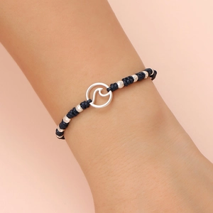 Detail of blue braided nautical bracelet with silver wave charm and faceted metal beads