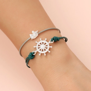 Detail of leather cord bracelets featuring silver unicorn and ship wheel charms on wrist