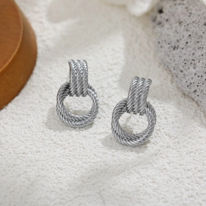 Macro detail of silver twisted rope texture earrings on a natural stone display