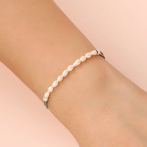 Detailed view of handmade pearl bracelet with grey leather cord on wrist