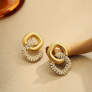 Détail de boucles d'oreilles double boucle plaqué or 18 carats avec perles et métal torsadé