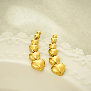 Übertriebene 18k goldene Herz-Ohrhänger präsentiert auf einem weißen Keramikteller