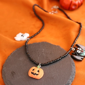 Nahaufnahme der Halloween-Halskette mit Geist-, Kürbis- und Fledermausanhängern auf Stein