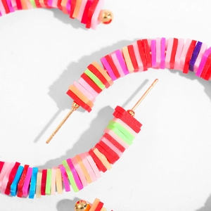 Close-up of bohemian colorful polymer clay bead hoop earrings with golden studs