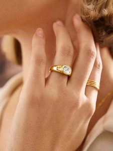 Gros plan d'une bague en or 18 carats avec zircone ronde portée avec d'autres bijoux