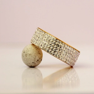 Anello in acciaio inossidabile dorato con 5 file di cristalli su un supporto moderno