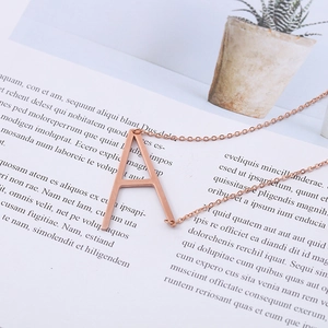 Detail of rose gold alphabet A pendant on a thin chain over a white book page