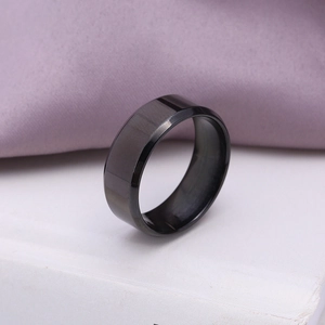 Black brushed stainless steel ring with polished beveled edges for men on white book