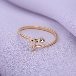Detailopname van gouden V-vormige roestvrijstalen ring met glanzende kristalsteen