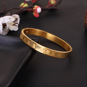 Minimalist gold titanium steel bangle featuring engraved Roman numerals on black stand