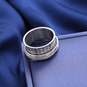 Stainless steel spinner ring with floral engraving on a blue jewelry box display