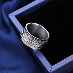 Spinner ring with embossed floral pattern in stainless steel on blue silk background