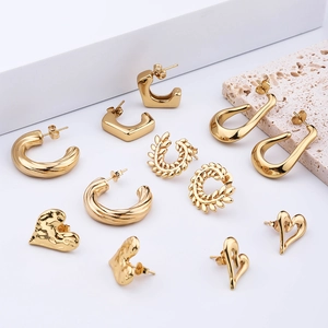 Set aus massiven goldenen Ohrringen mit Herz- und Creolen-Design auf Naturstein