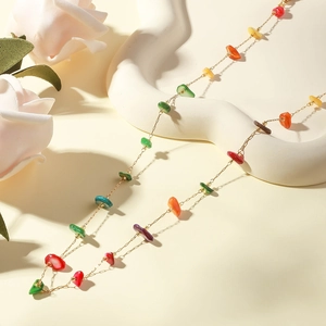 Detailed shot of a gold necklace featuring colorful irregular stones and floral accents