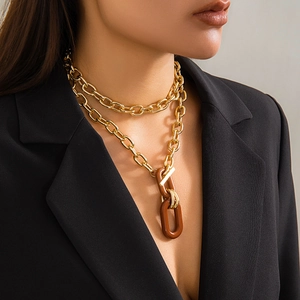 Close-up of double-layered chunky gold chain with a brown resin oval pendant and T-bar clasp