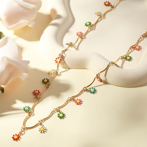 Detail of gold necklace featuring multi-color enamel daisy charms on a wave display