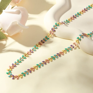 Colorful enamel leaf necklace in gold finish displayed on an elegant cream tray with a rose