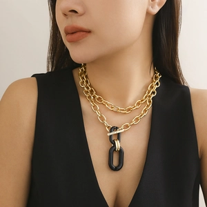Detail of layered gold metal chunky chain necklace with toggle clasp on model