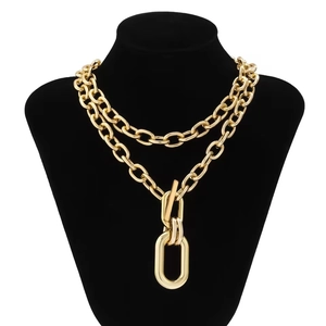 Detail view of double-layered chunky gold chain necklace with large oval pendant on mannequin