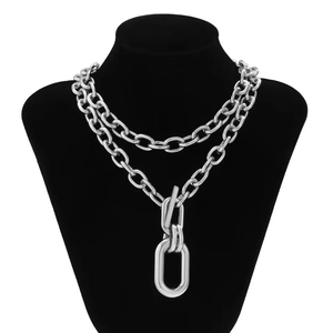 Punk style chunky layered silver chain necklace with a large oval pendant on neck model